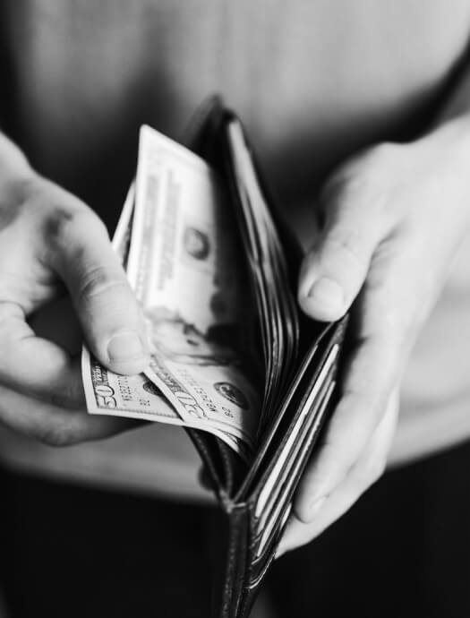Person holding wallet filled with cash