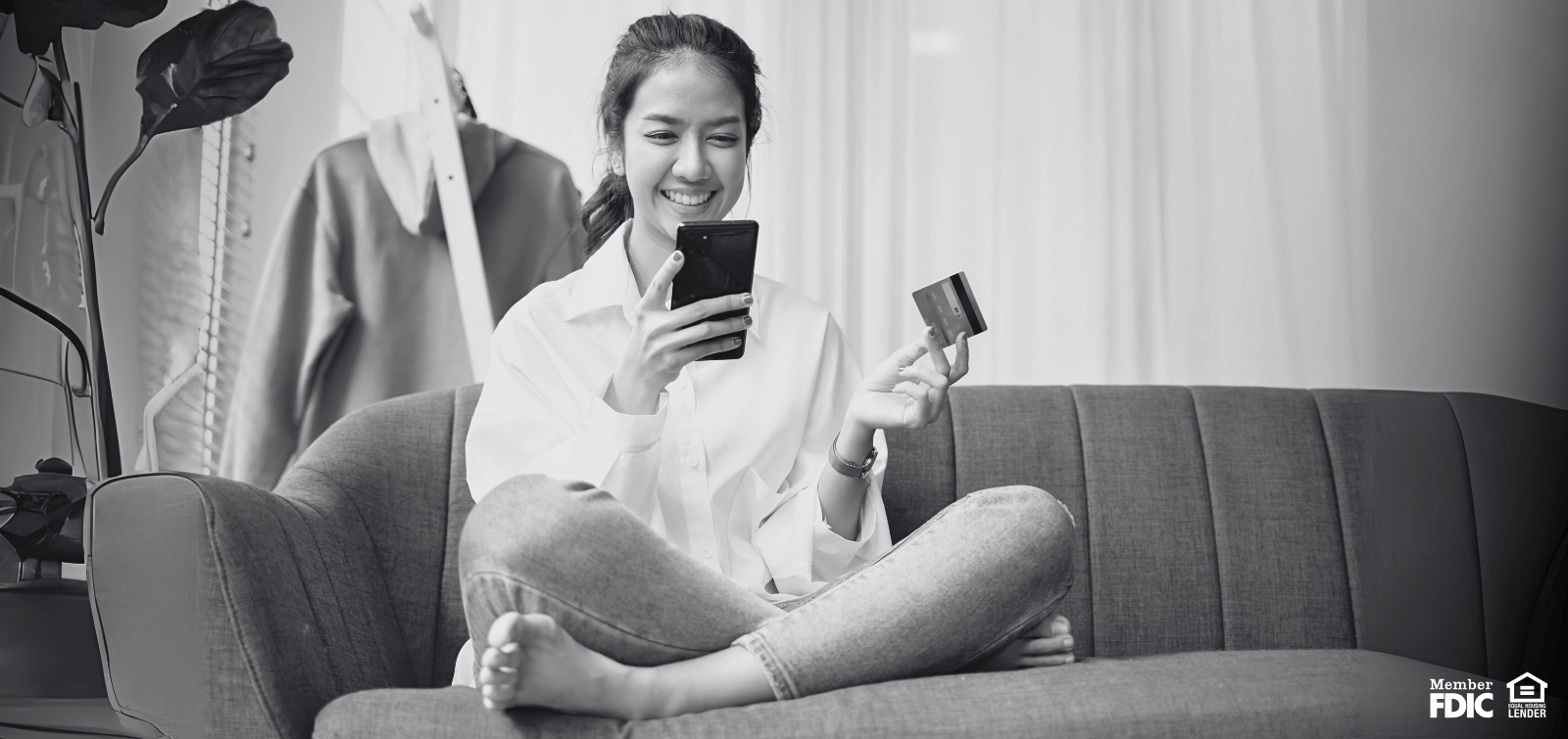 young woman using her debit card to purchase something on her phone