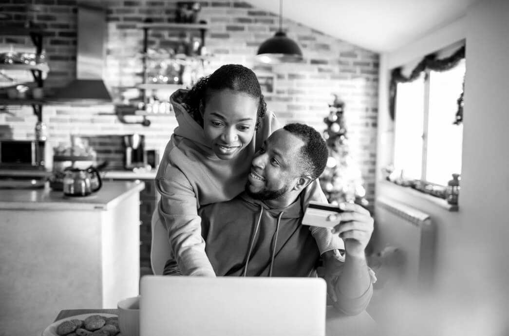 Father and teenage daughter at laptop together while father holds debit card to make an online purchase